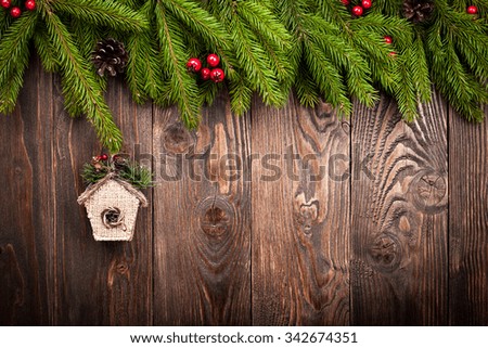 Decorated fir tree and birdhouse on dark brown wooden background