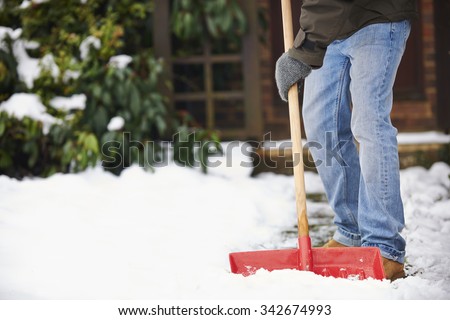 Man Clearing Snow From Path With Shovel Royalty-Free Stock Photo #342674993