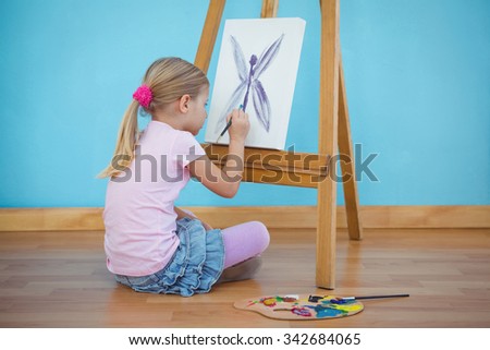 Girl sitting down painting a picture on an easel