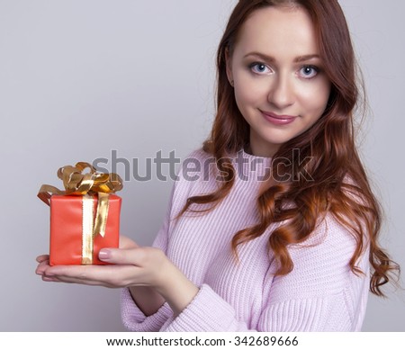 beautiful young woman with red hair cheerfully posing with christmas present