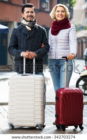 Elderly woman and her husband with luggage going to hotel