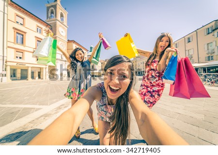 Three pretty girls walking on the streets and holding shopping bags - Best friends shopping on a sale event and taking a selfie