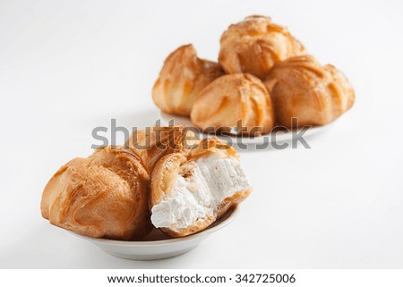 Coffee in the white cup and eclairs with cream on a white background