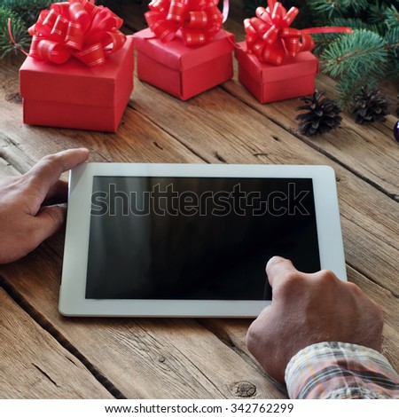 Square frame. Man clicks on the blank screen tablet computer closeup. The concept of buying Christmas gifts via the Internet.  Copy space. Free space for text. Top view. 