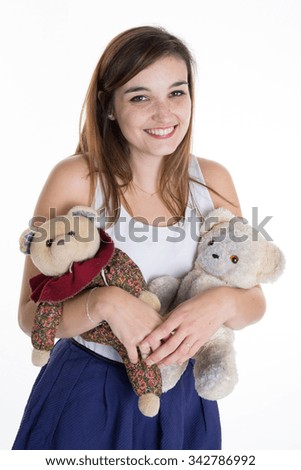 Lovely smiling young woman holding soft teddy bear on isolated blue background