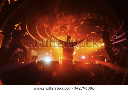 DJ hands up with crowd of people in night club party under red light Royalty-Free Stock Photo #342796886