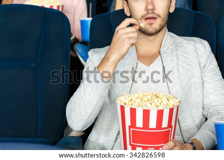 Best snack for cinema. Cropped shot of a man eating popcorn in a movie theater