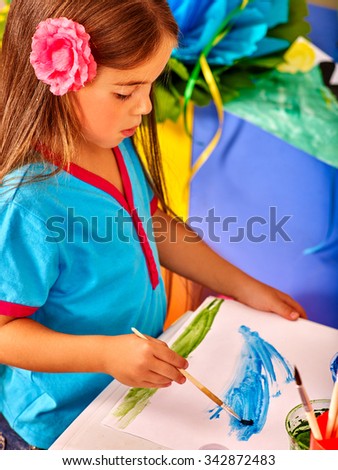 Beauty little girl with brush painting on table in  kindergarten . 