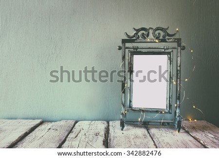 low key image of old victorian steel blue blank frame with fairy garland lights. faded retro filtered image