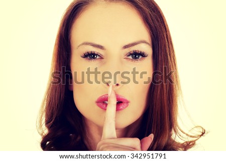 Serious woman placing finger on lips.