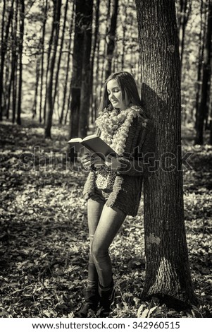Portrait of a beautiful teenage girl reading a book in the forest,autumn season 