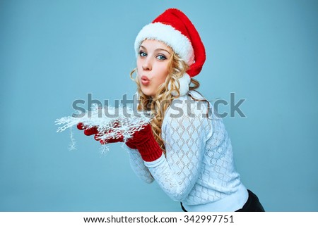 Beautiful young woman in Santa Claus clothes with snowflakes on a blue background