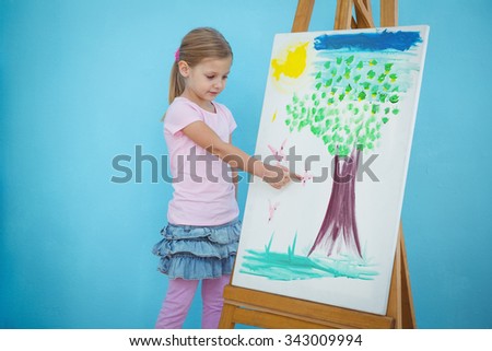Smiling girl pointing to her picture on an easel