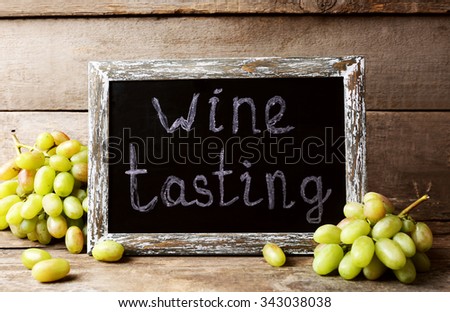 old square chalk scripted frame with grape on wooden background