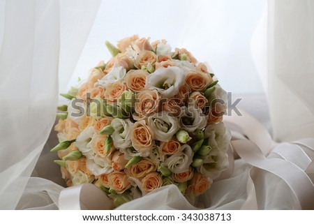 Photo closeup front view ball-shaped elegant wedding bouquet of fresh pastel pink white roses flowers buds with ribbons for bridal ceremony on white curtain lace background, horizontal picture 