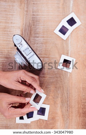 View of hands holding photo slides against wooden plank