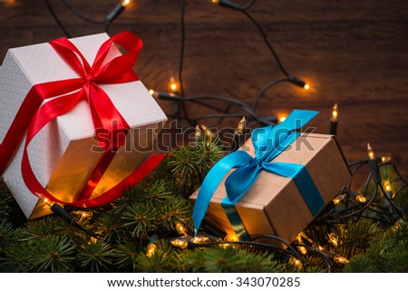 Christmas gift boxes with red and blue bows and bokeh lights on wooden surface