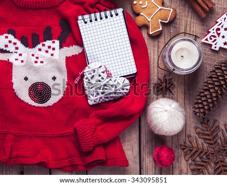 Christmas set. Warm blanket, sweater with a deer, candle, notebook, spices, cinnamon, pine cones, heart  on the wooden background