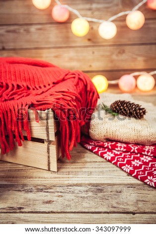 Christmas set. Warm blanket, sweater, socks, garland and a bump on the wooden background