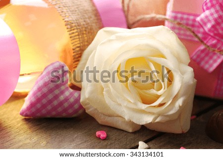 A white rose and a gift in the box, on wooden background, close-up