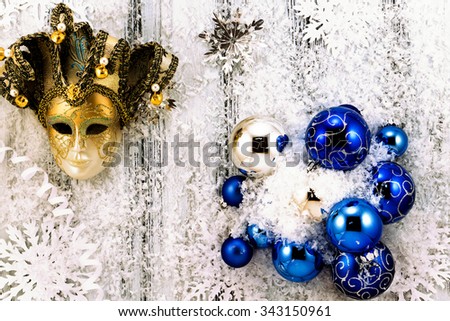 New year theme: Christmas tree white and silver decorations, blue balls, snow, snowflakes, serpentine and golden mask on white retro stylized wood background contrasted