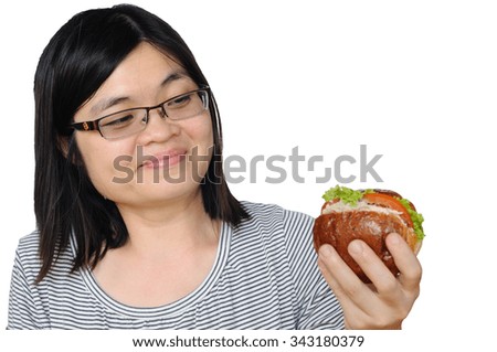 Asia middle aged woman is enjoy to eat double hamburgers.