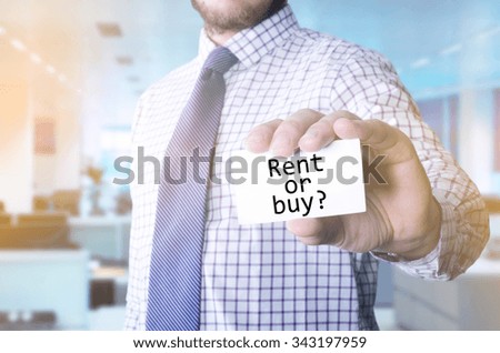 Man in office holding a card with a message text written on it Rent or buy ?