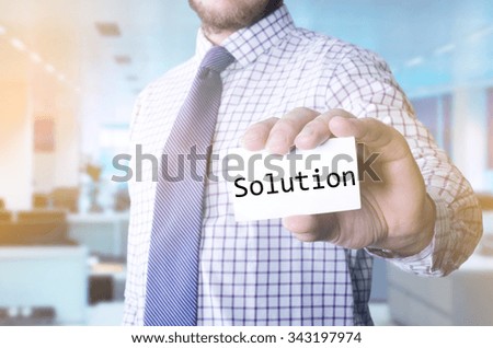 Man in office holding a card with a message text written on it Solution
