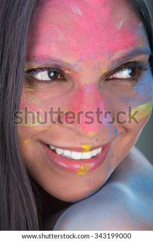 Closeup portrait of pretty latin girl looking to the side with painted face over gray background