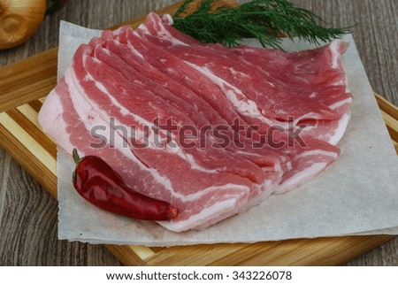 Raw bacon on the wood board with dill leaves