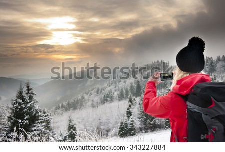 Young blonde woman taking picture of sunset in Jeseniky mountains, Czech Republic