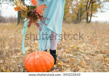Girl with autumn bouquet and a large pumpkin in the park. A wedding in the style of boho. Copy space.