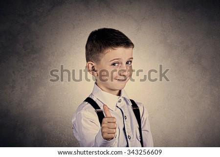 Little boy with thumb up gesture isolated over grey background.Portrait of confident happy little boy showing thumbs up gesture wearing costume  isolated over grey background.Funny,happiness.