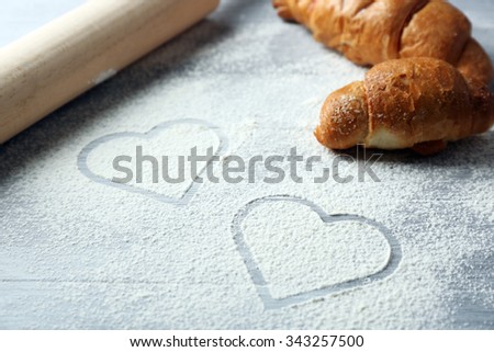 Hearts of flour and rolling pin on light background