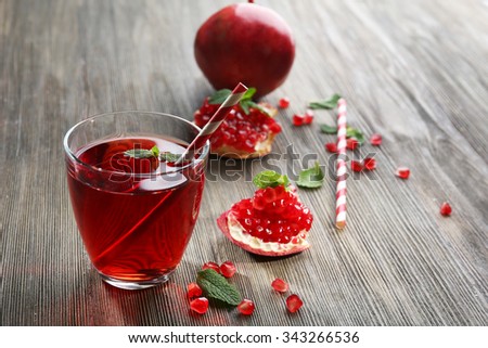 A glass of tasty juice and garnet fruit, on wooden background