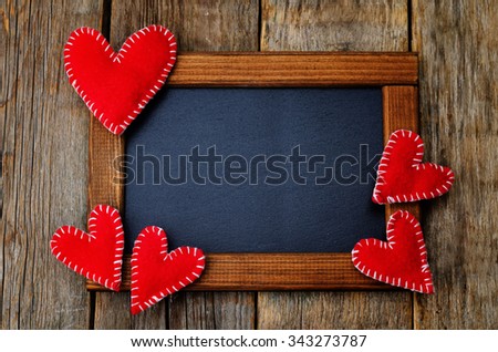 Toy hearts on a frame with a chalkboard on a dark wood background. toning. selective Focus