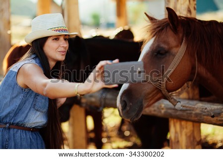 happy woman taking selfie photo with horse with smartphone camera