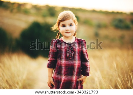 Beautiful little girl in a dress walks on nature