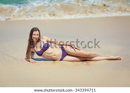 Young beautiful girl in the swimsuit  is lying on the sand near ocean