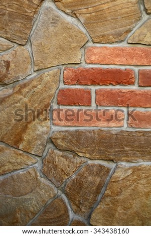 Photo closeup outdoor wall made of brown sandy stones and red bricks facade exterior of rocks tiles of various sizes forms on mural background, vertical picture 