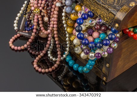 Jewelry box with natural semiprecious stones necklaces and bracelets on black background