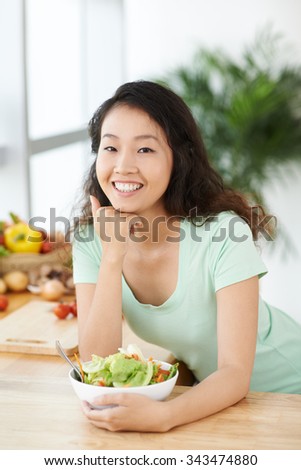 Portrait of cheerful young woman with a bowl of salad