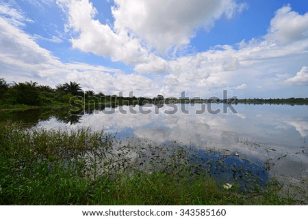 Calm lake with beautiful reflection of cloud and blue sky during sunny day. Nature composition