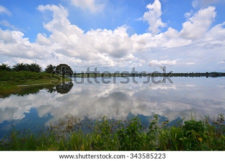 Calm lake with beautiful reflection of cloud and blue sky during sunny day. Nature composition