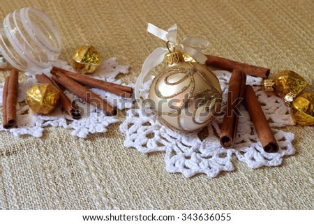 Festive composition for table decorations. Fragrant cinnamon sticks and glass decorations on knitted snowflakes.