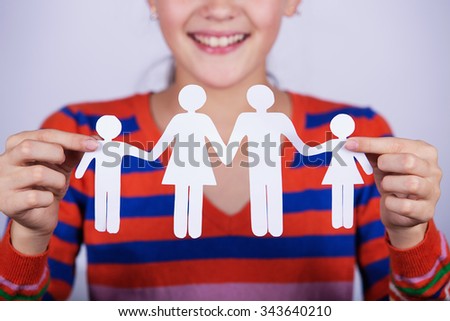 Smiling little girl holding paper cut of family.Family Life Insurance.Protecting family, family concepts. 