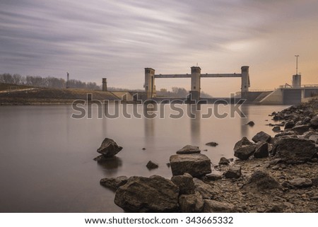 Dam in dusk on the river with rocks