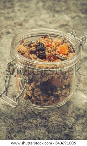 Quinoa granola in open glass jar on marble stone background, toning, vintage, aged