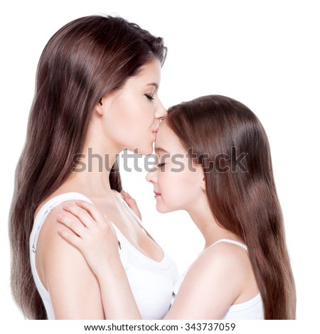Beautiful young mother with a small daughter 8 years with long hair at studio 