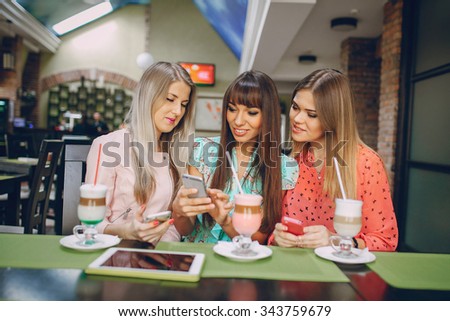 Three beautiful girls in cafes new gadgets are photographed and show photo